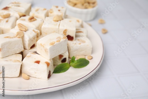 Pieces of delicious nutty nougat on white table, closeup
