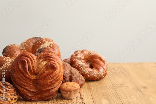 Different tasty freshly baked pastries on wooden table, space for text