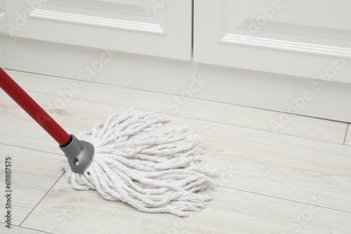 Cleaning white parquet floor with mop  closeup