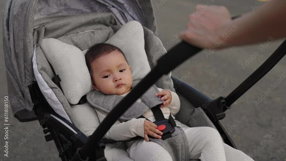 infant baby in stroller with mother pushing while walking in the park infant baby in stroller with mother pushing while walking in the park