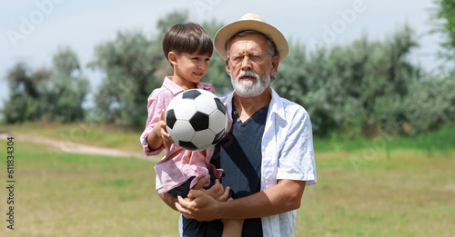 Little boy with ball for playing football and his grandfather in park © Pixel-Shot