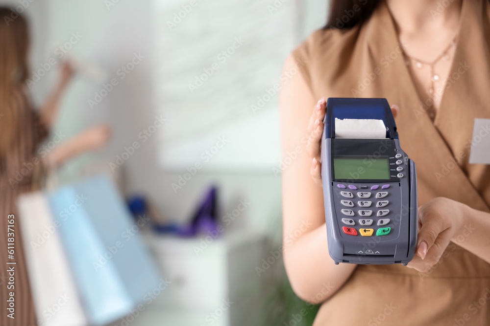 Female sales assistant with payment terminal in shoe shop, closeup Female sales assistant with payment terminal in shoe shop, closeup