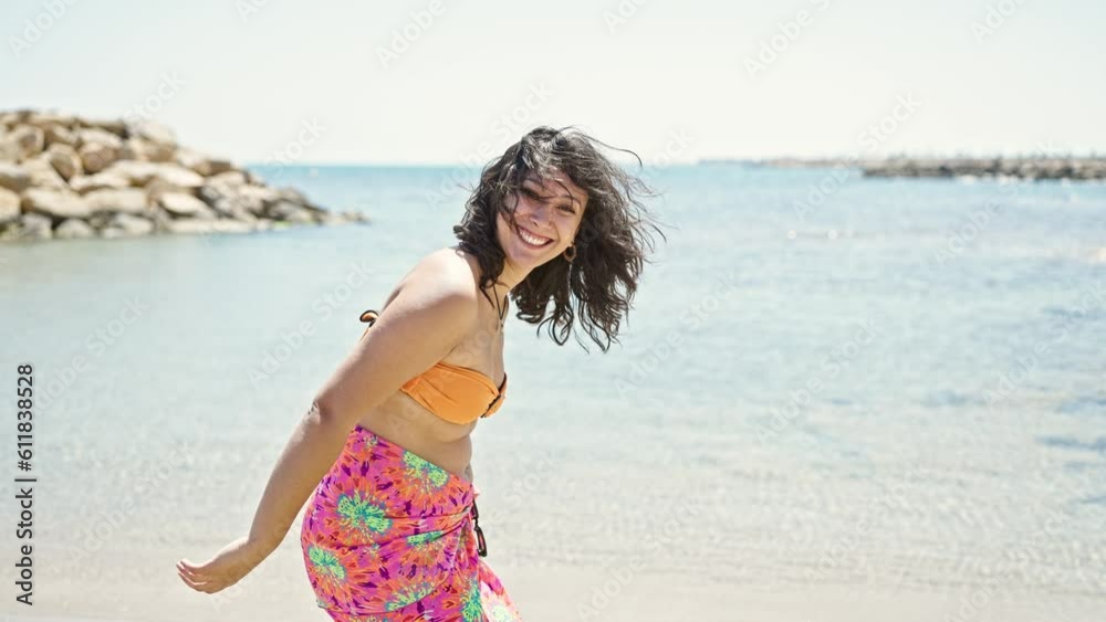 Young beautiful hispanic woman tourist smiling confident wearing bikini at beach