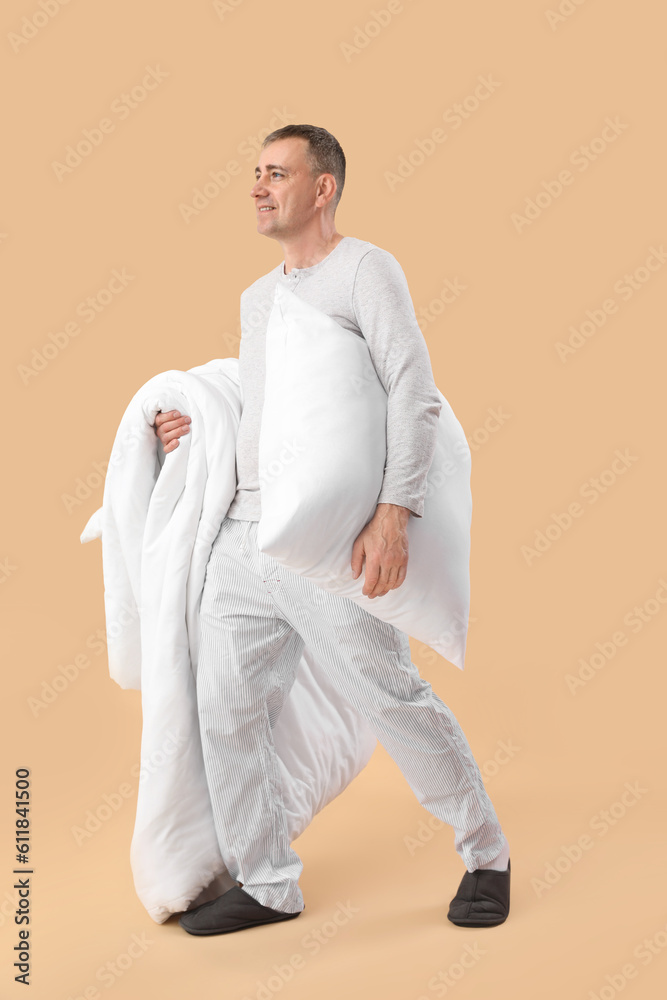 Mature man with soft pillow and blanket on beige background Mature man with soft pillow and blanket on beige background