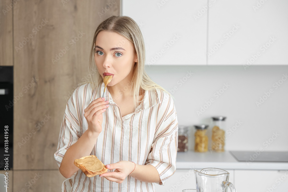Young woman spreading tasty nut butter onto toast in kitchen Young woman spreading tasty nut butter onto toast in kitchen