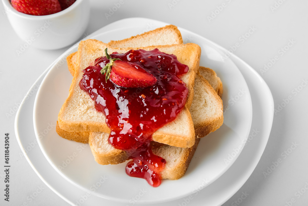 Plates and tasty toasts with strawberry jam on white background Plates and tasty toasts with strawberry jam on white background