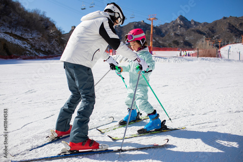 Little girl learning how to ski with her coach photo