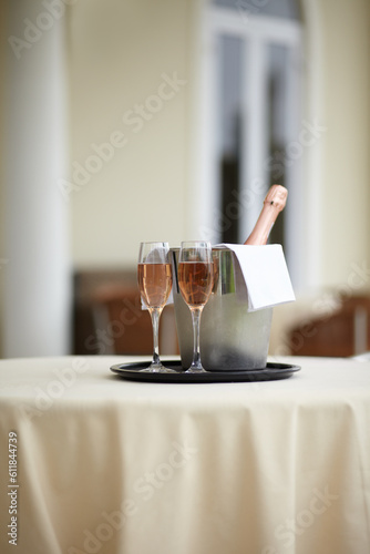 Hotel, bottle and glasses of champagne on a table for luxury service, celebration and hospitality. Restaurant, wealth and wine, alcohol and drinks at a fine dining establishment for an experience