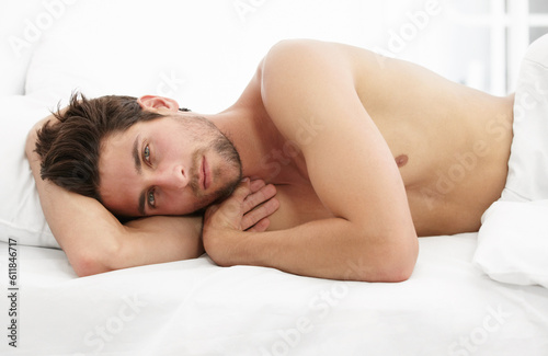 Sexy portrait, man in bed and morning wake up time with sensual pose, relax and rest in apartment. Sleep, relaxing and handsome, tired topless male model with muscle waking in bright bedroom of home.