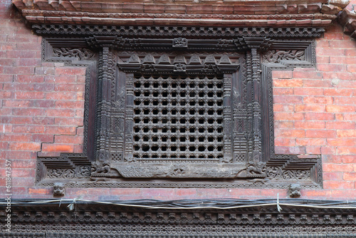 Fragment of ancient Nepalese architecture in Bhaktapur, Nepal. Antique wooden window with bars. Decorative woodcarving.