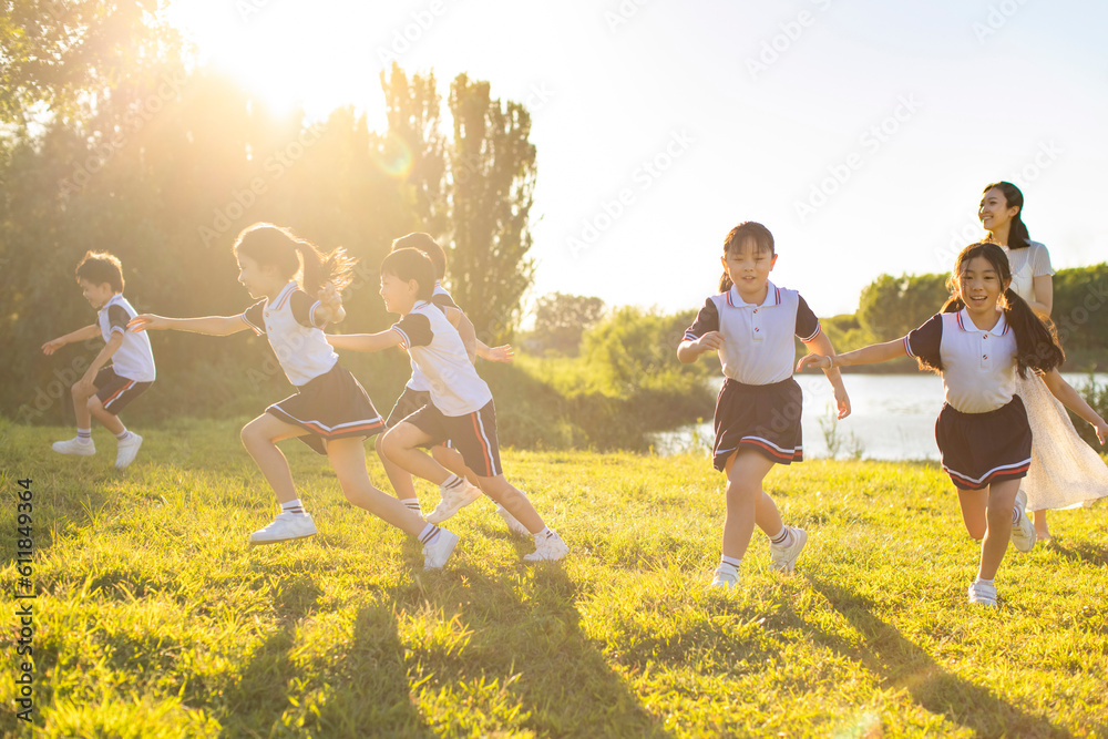 Cheerful school children and their teacher playing in park Cheerful school children and their teacher playing in park