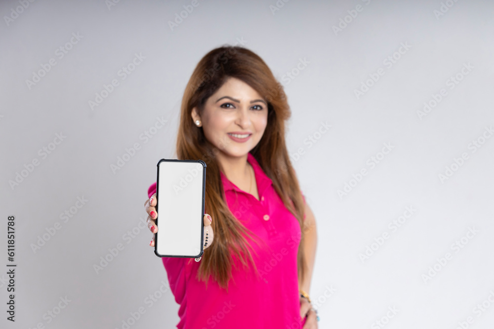 Indian woman standing and showing smartphone screen on white background. Indian woman standing and showing smartphone screen on white background.