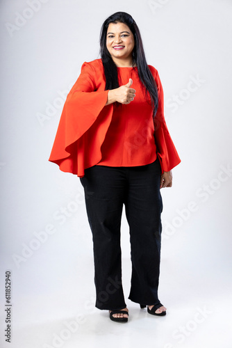 Confident indian woman showing thumbs up on white background. © Niks Ads
