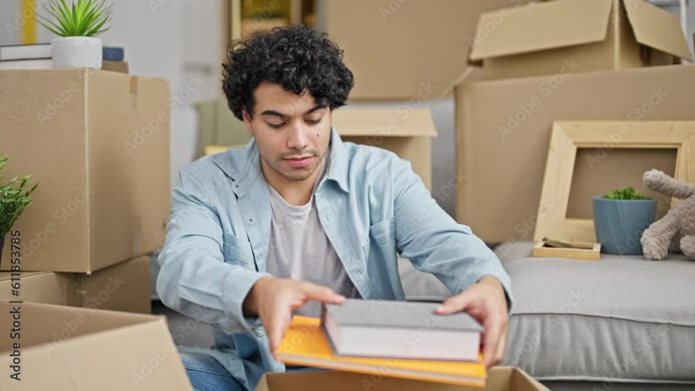 Young latin man packing cardboard box hugging photo at new home Young latin man packing cardboard box hugging photo at new home
