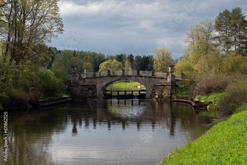 View of the Slavyanka River and the Viscontiev Bridge in the Pavlovsk Palace and Park Complex on a sunny spring day, Pavlovsk, Saint Petersburg, Russia