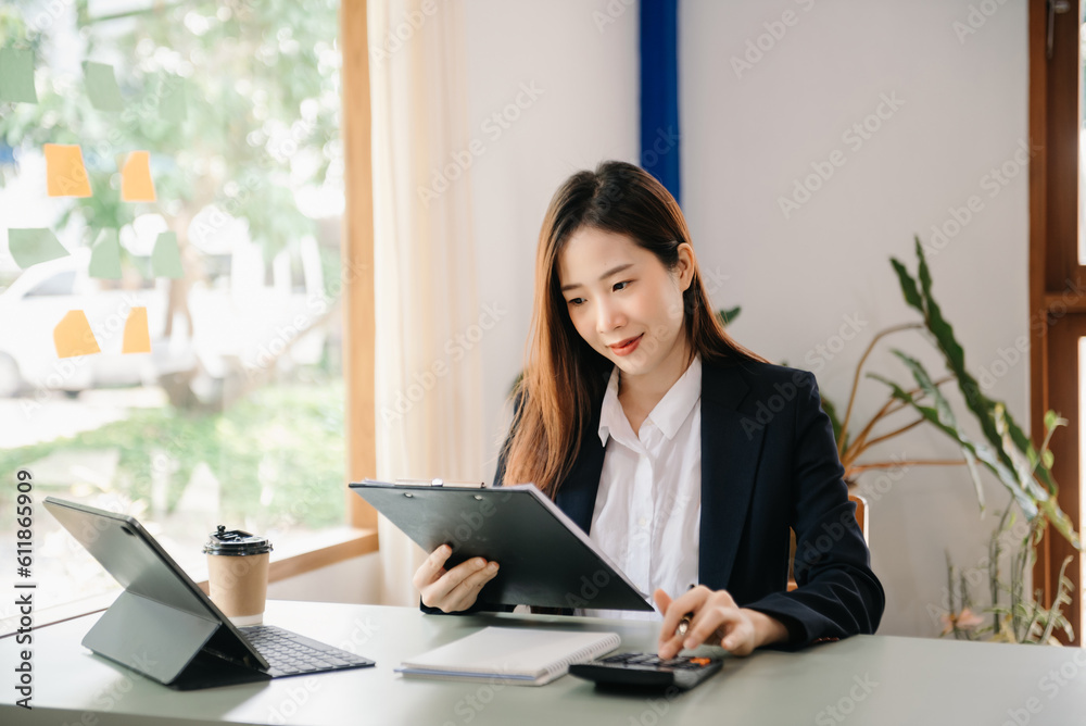 Young attractive Asian female office worker business suits smiling on desk in home office Young attractive Asian female office worker business suits smiling on desk in home office