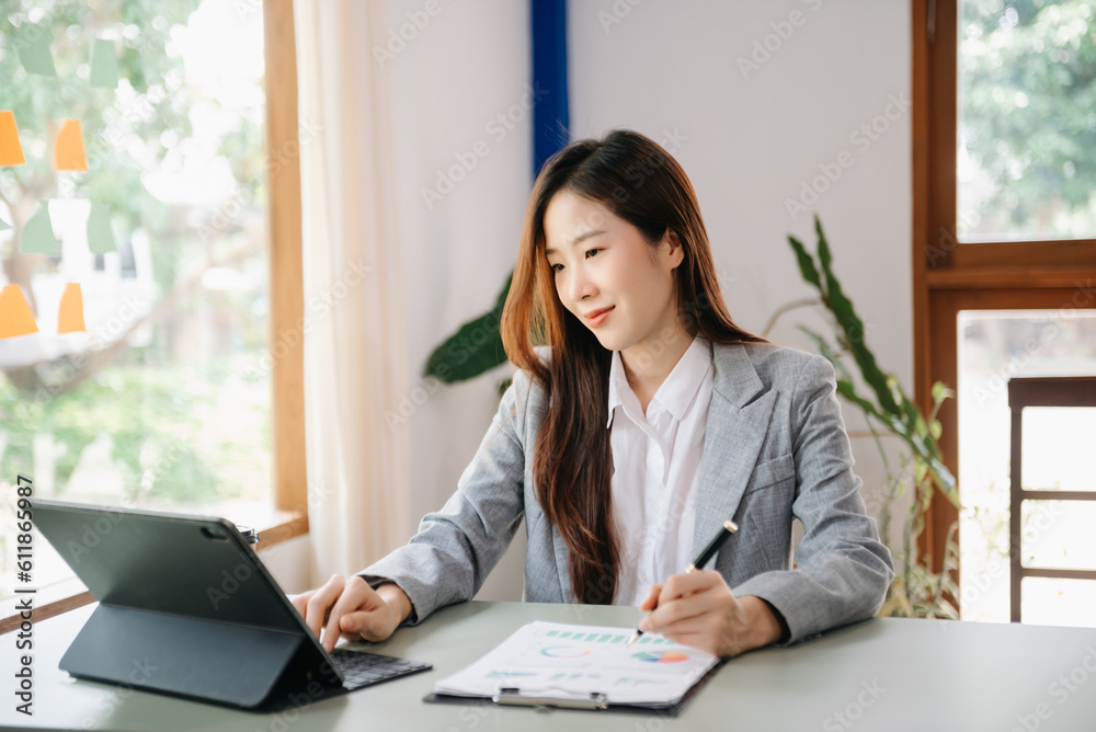 Young attractive Asian female office worker business suits smiling on desk in home office Young attractive Asian female office worker business suits smiling on desk in home office