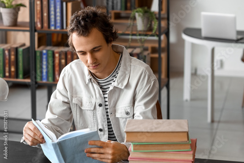 Young man reading book at table in library