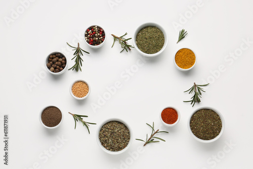 Frame made of bowls with spices and rosemary on light background