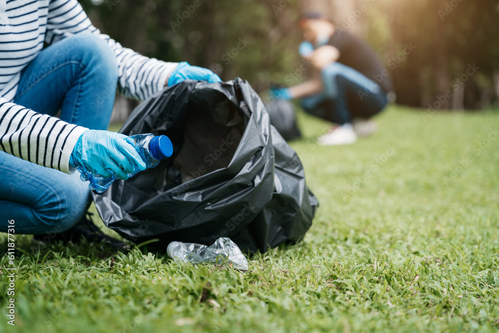 People holds plastic and glass waste bottles into recycling bags for cleaning at the park.