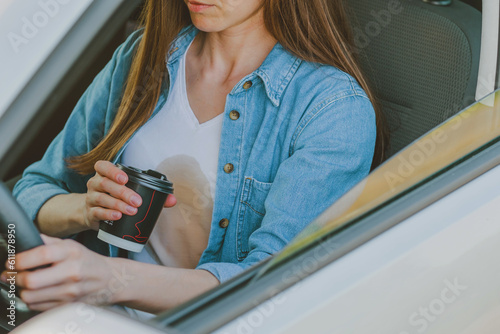 Female spilling coffee or tea on herself while driving a car. Dirty coffee stain. Spoiled clothes. daily life stain concept