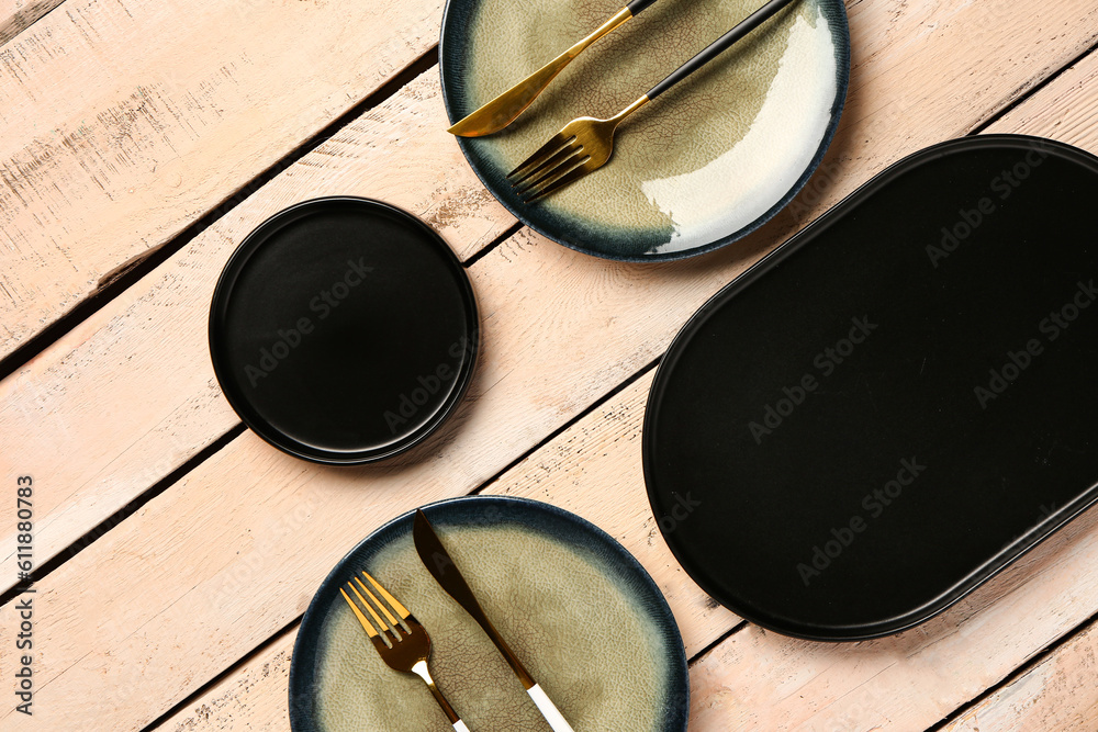 Composition with clean plates and cutlery on beige wooden table Composition with clean plates and cutlery on beige wooden table