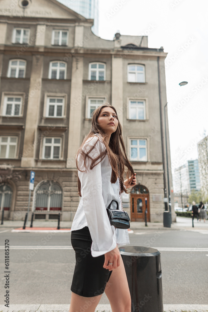 Pretty young beautiful woman in fashion casual clothes with white shirt and black dress walks in the city