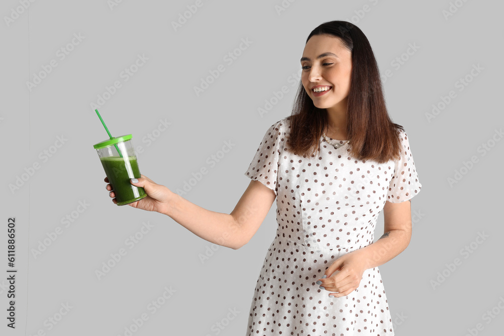Young woman with glass of vegetable juice on grey background Young woman with glass of vegetable juice on grey background