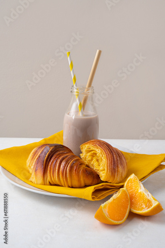 Freshly baked portuguese Brioche croissants on a plate with chocolate milk and orange pieces. Tipical portuguese breackfast photo