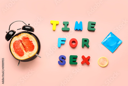 Text TIME FOR SEX, condoms and alarm clock with grapefruit on pink background