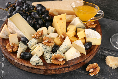 Fotografija Plate with pieces of tasty cheese on dark wooden background
