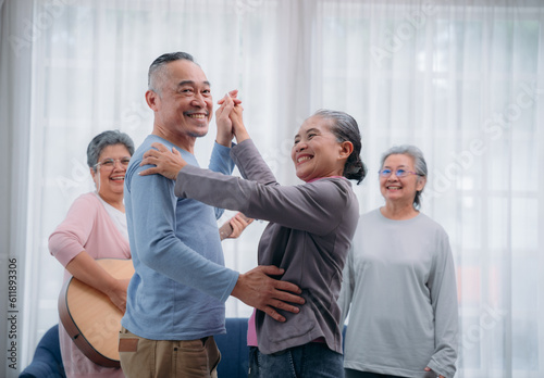 Senior friends are dancing and playing a musical instrument at residence. Asian senior's hobbies and interests. Senior lifestyle at home.