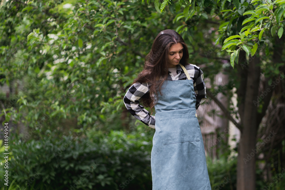 young female gardener is putting on and tighting an apron before work young female gardener is putting on and tighting an apron before work