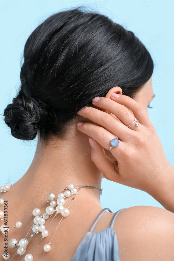 Young woman with beautiful jewelry near blue wall