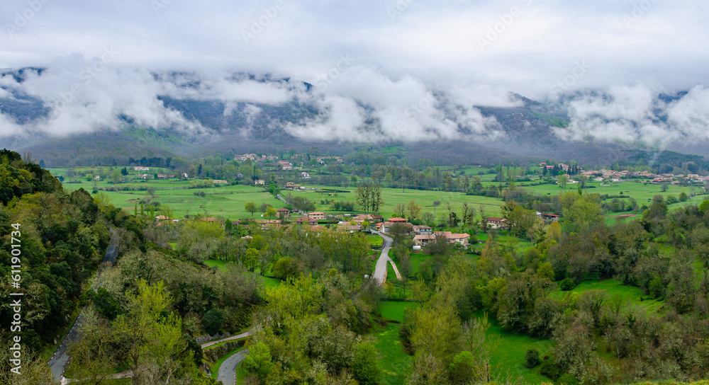 Magical landscape green scenery of Spanish valley. Clouds sitting in a valley over a small village. Overcast cloudy day.