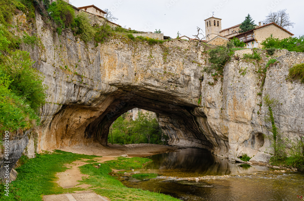 Natural bridge in the village Puentedey formed by a flowing river. Tunnel within rock underneath a village in Spain. 
