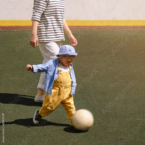 Fotografie Baby boy with woman mother is practicing soccer skills on the field in the yard