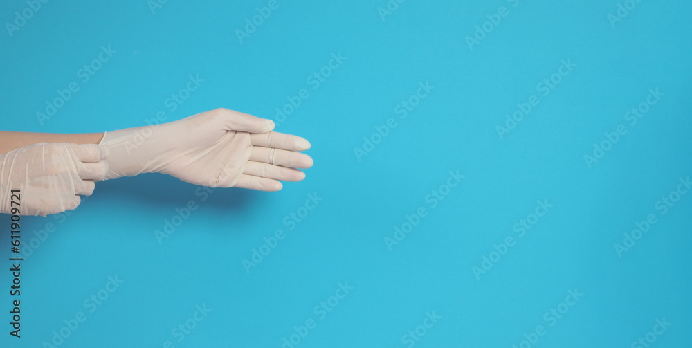 The hand is wearing and pull white latex gloves on a blue background.