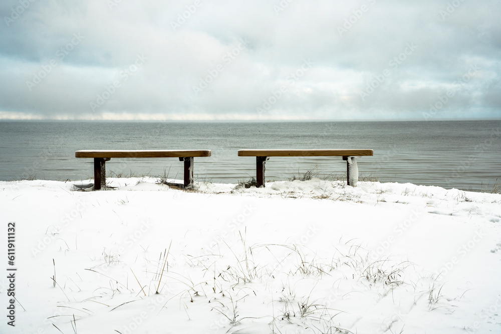 two romantic benches on the shore of the snowy sea