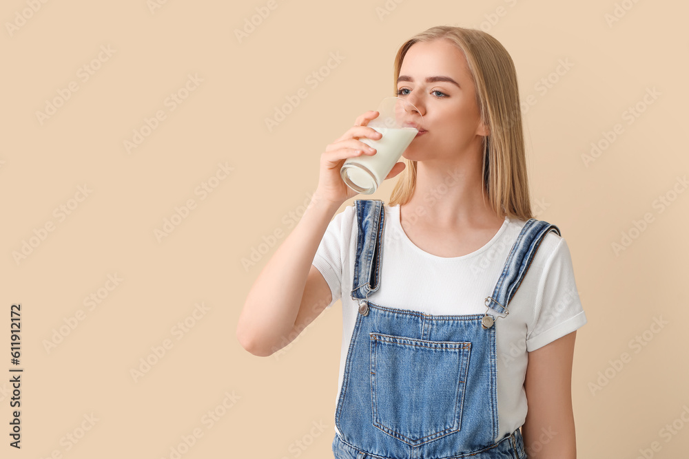 Beautiful young woman drinking milk on beige background Beautiful young woman drinking milk on beige background