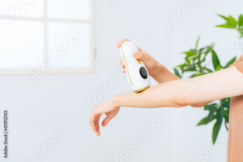 Obraz na plátne A woman using an epilator to remove unwanted arm hair at home.
