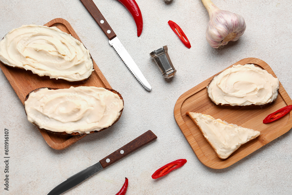 Wooden boards of tasty sandwiches and toast with cream cheese on light background