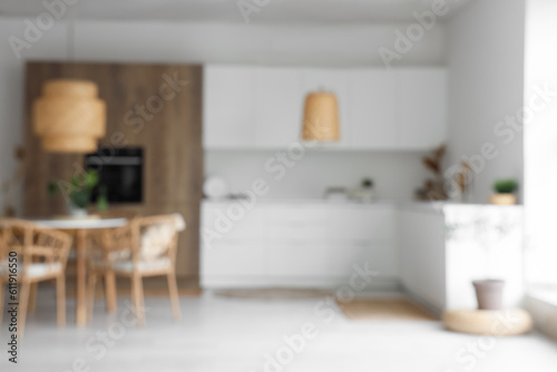 Interior of light kitchen with built-in oven  table  chairs and white counters  blurred view