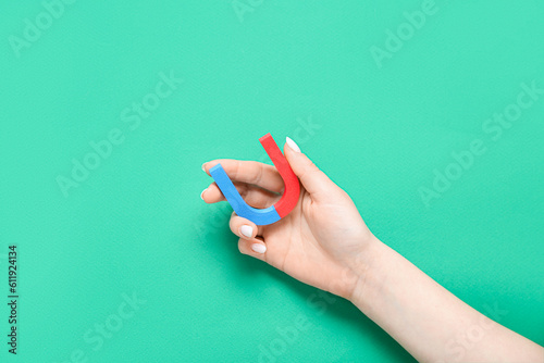 Female hand with mini magnet on green background