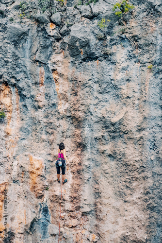Alone woman climbing on a huge cliff in mountains © EdNurg