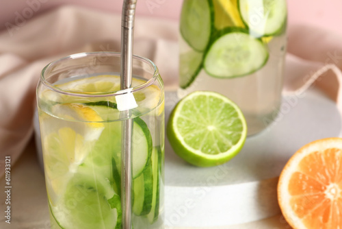 Glass and bottle of infused water with cucumber slices, closeup