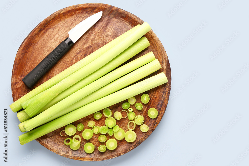 Board with slices of fresh leek on grey background