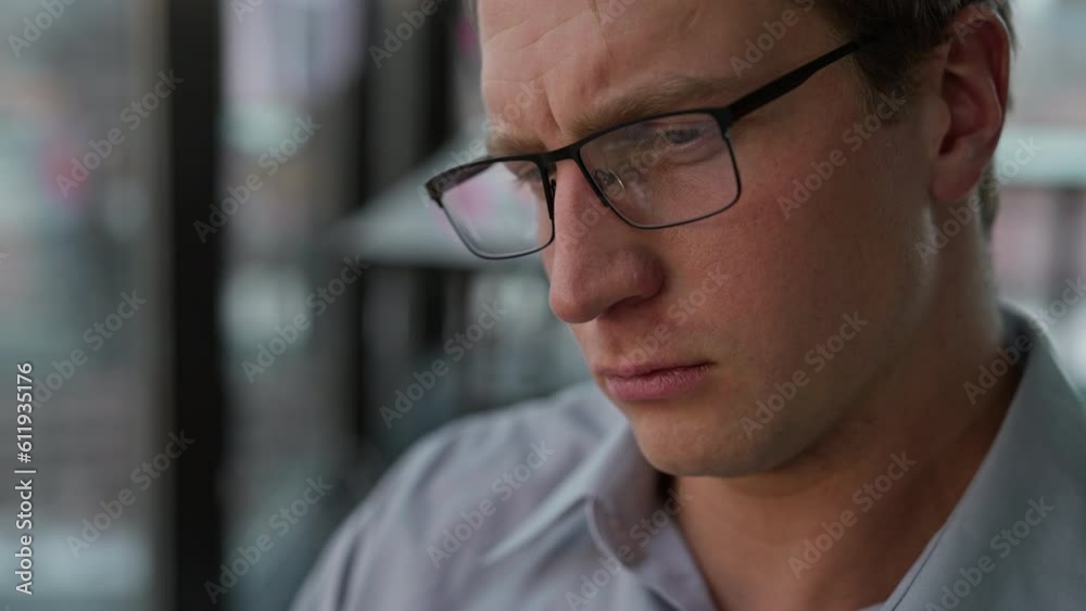 Tired businessman sits at window and expresses dissatisfaction Tired businessman sits at window and expresses dissatisfaction