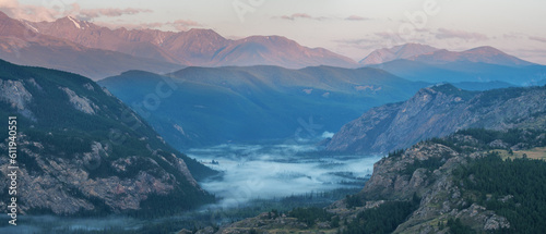 Fog in the mountain gorge and peaks in the evening light, panoramic view