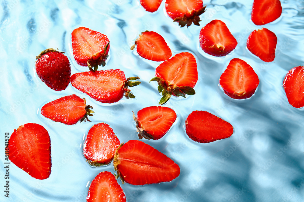 Slices of fresh strawberry in water on blue background Slices of fresh strawberry in water on blue background
